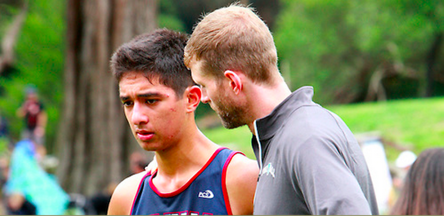 Coach Buckley coaches senior runner, Julian Moreno 16, at a meet last year. 