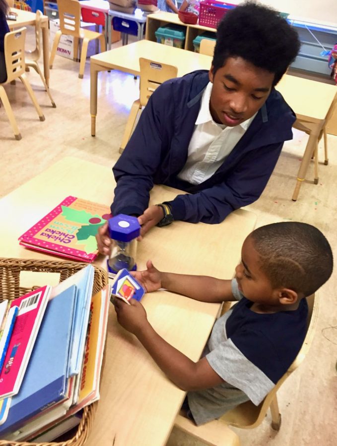 Phoenix Aquino-Thomas ’18 plays with a student during his lunch break as a part of the service requirement for his theology class. Students engage in service at sites all around the city. 