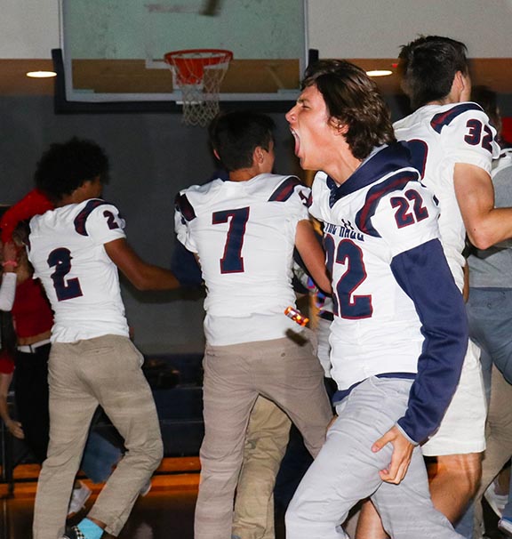 Junior Owen ODell runs out with the football team during the Pep Rally on Sept. 13. The event started Spirit Week, which will feature two games, a dance and special dress days.