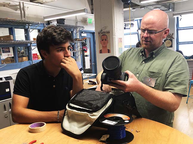 Liam Carey, Computer Science and Digital Design instructor, shows junior Eon Kounalakis a Sony camera from the Digital Media Library. In preparation for the school year, the Department of Tech and Innovation set up AssetTiger, a program that facilitates keeping track of the equipment and sends notification emails to users.