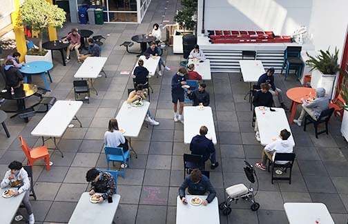Students eat lunch in the Courtyard of the Pine/Octavia campus. The 15 long tables accommodated two people at a time, and 11 round tables accommodated one person.