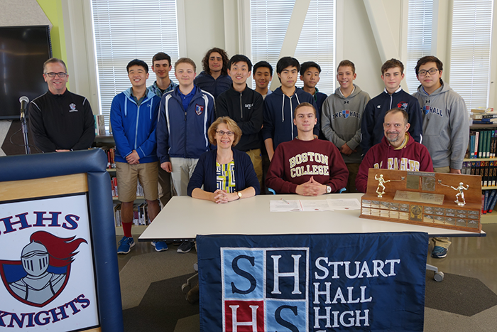 Students and family join Zack as he signs his letter of intent to attend Boston College.