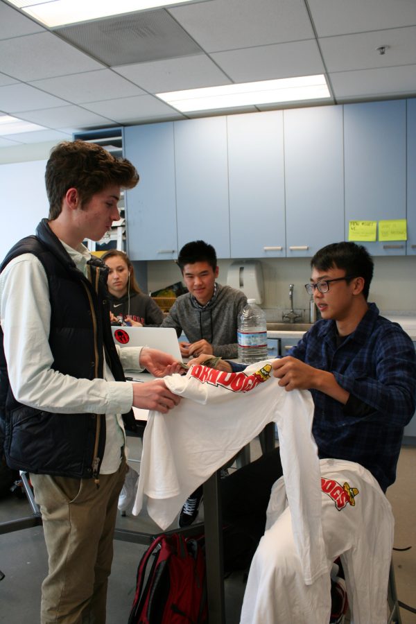 Michael Liu ’18 sells a shirt to Dylan Kelly ’17 at the end of art class in Siboni. Liu founded his shirt company with a few of his friends and has been selling shirts at school for the majority of the second semester.