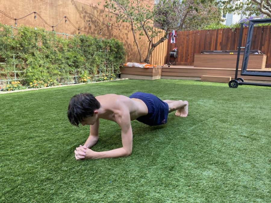 Senior Vasco Travis holds a plank in his backyard during the summer in preparation for football. Although fall sports were postponed until January, athletes are staying in shape by either working out by themselves or following an Athletics Department program.