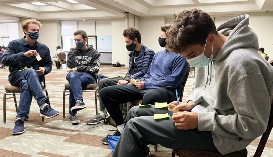 Senior Chase Mack writes down highs and lows from each year of high school on Post-its prior to sticking them to a wall during a Senior Retreat activity. Seniors separated into their advisories and took turns walking around the venue to put up and read each others memories.