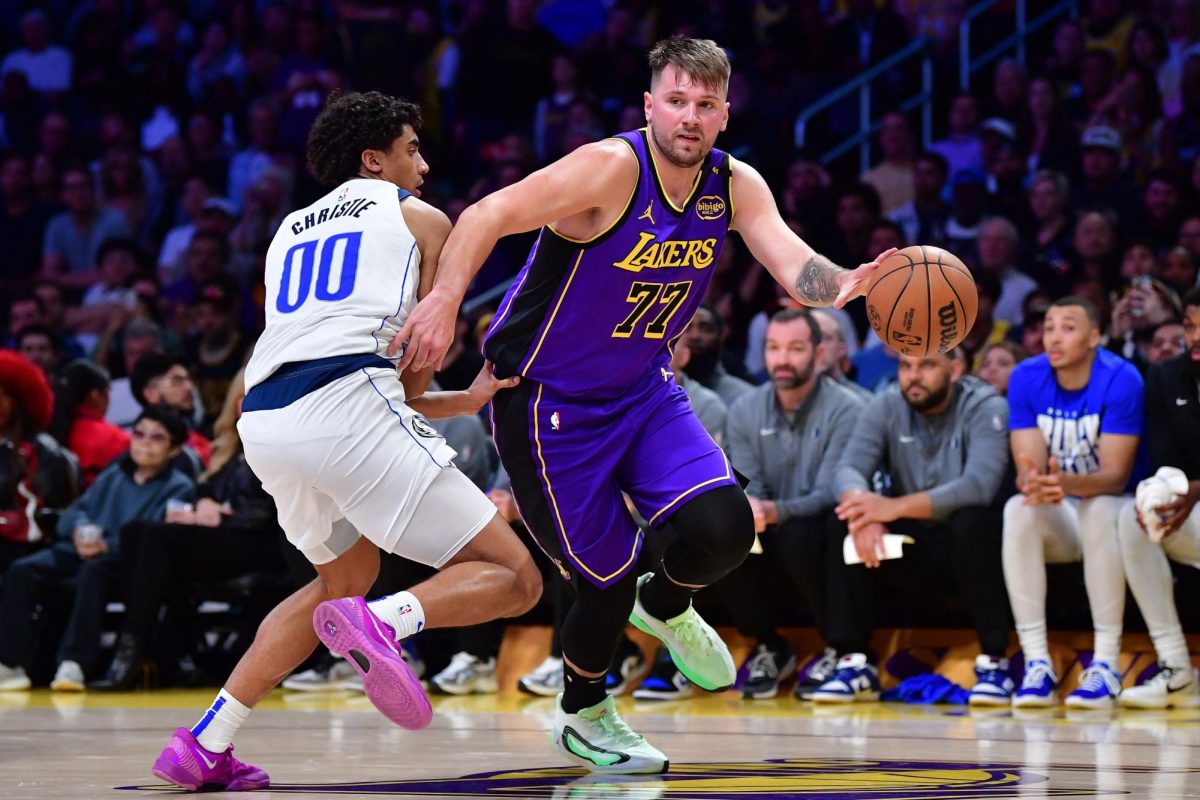 Feb 25, 2025; Los Angeles, California, USA; Los Angeles Lakers guard Luka Doncic (77) dribbles the ball past Dallas Mavericks guard Max Christie (00) during the second half at Crypto.com Arena.